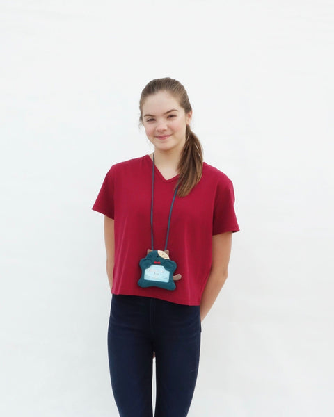 Woman with a teal green cat ID card Badge holder with two paws holding the PVC window, a lanyard attached, and a zipper pocket in the back