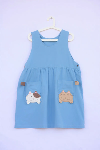 Cute blue cat dress with cats and cat tails on pockets. Buttons are on the cat dress.