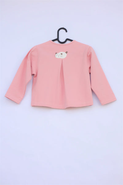 A pink girlsâ boxy-fit cotton cat jacket on a hanger with an appliquĂ© cat sleeping on the back. There is a pleat on the back of the jacket.
