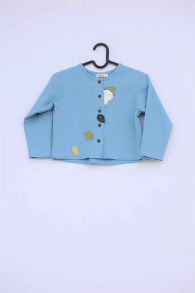 A blue girlsâ boxy-fit cotton cat jacket on a hanger with appliquĂ© cat and leaves on the front. There are buttons on the jacket.