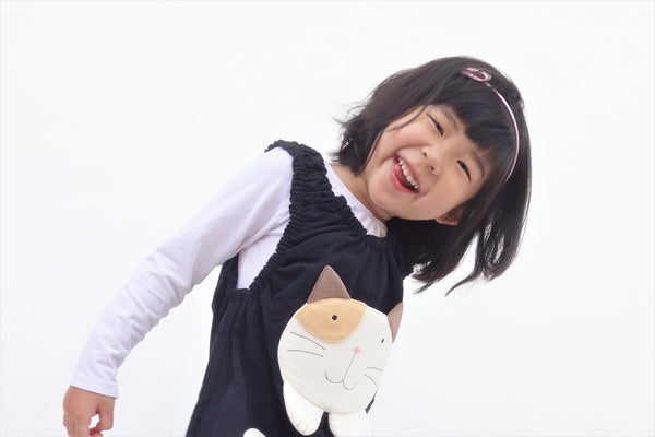 Smiling girl wearing  black, cat-themed jumper with large, soft cat face pocket on the front.