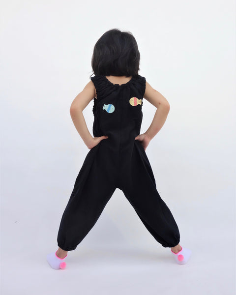 Girl wearing black, cat-themed jumper with two sewn-on appliqué fish swimming on the back.