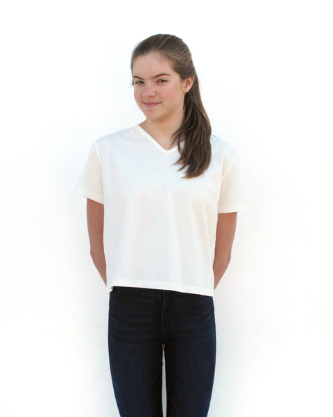 Woman wearing Cat Crop Top in white with V-neck and short sleeves in close-up front view.
