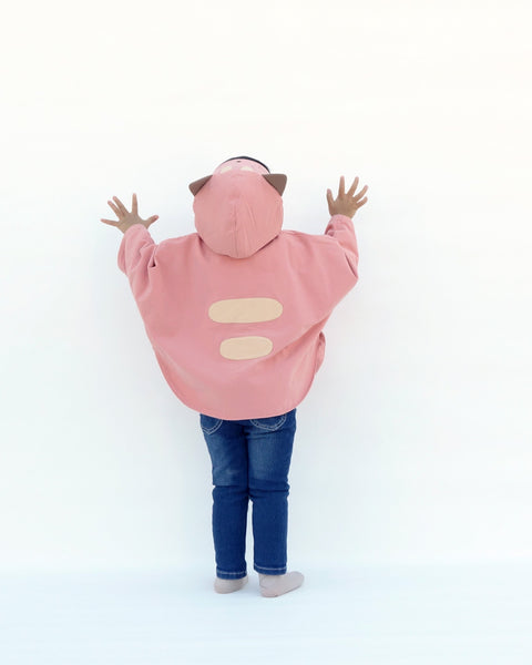 Toddler girl wearing pink kitten cape coat jacket with cat ears and face on the hood, cat paw pockets, and two cat stripes in back view.