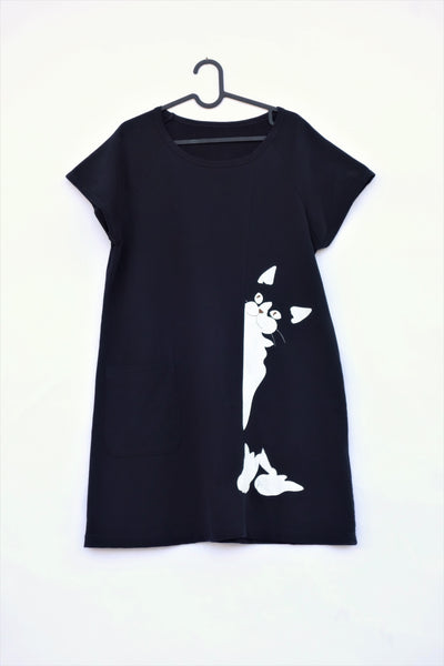 Woman's black, cat shift-dress with short sleeves, rounded neck opening, graphic cat design, on hanger, in front view.