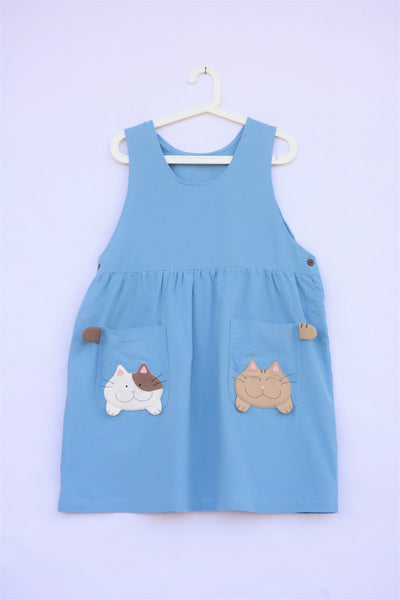 Cute blue cat dress with cats and cat tails on pockets. Buttons are on the cat dress. 