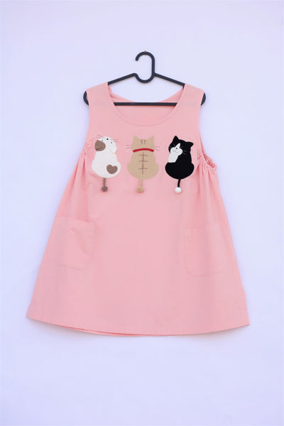 A cat-themed, cotton, pink shirt/mini A-line dress/top/tunic on a hanger with three appliqué cats on the front 