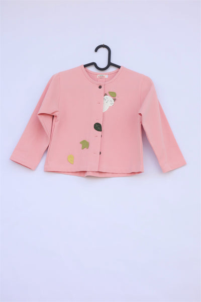 A pink girls’ boxy-fit cotton cat jacket on a hanger with appliqué cat and leaves on the front. There are buttons on the jacket.