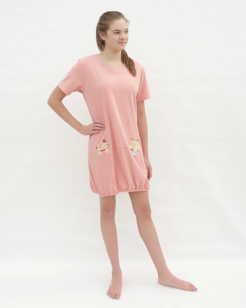 Woman wearing cat t-shirt dress in pink with cat appliqué, embroidery, front pockets, round neck opening, short sleeves, in 3/4 front view.