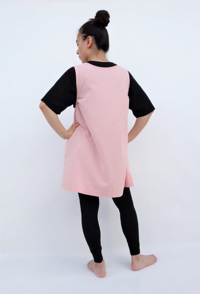 A woman standing and wearing a cat-themed, cotton, pink shirt/mini A-line dress/top/tunic, back view 