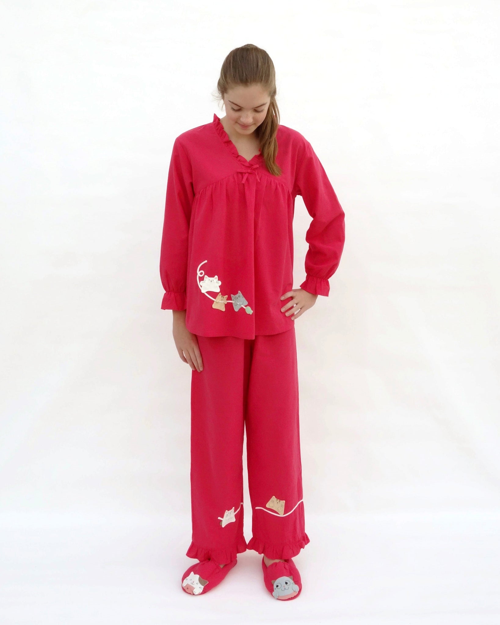 Women wearing red pajamas with cat appliqué, embroidery details, and matching slippers in front view.