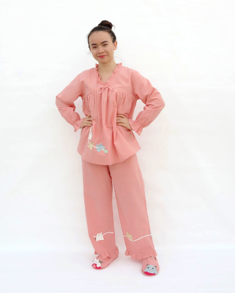 Women wearing pink pajamas with cat appliqué, embroidery details, and matching slippers in front view.