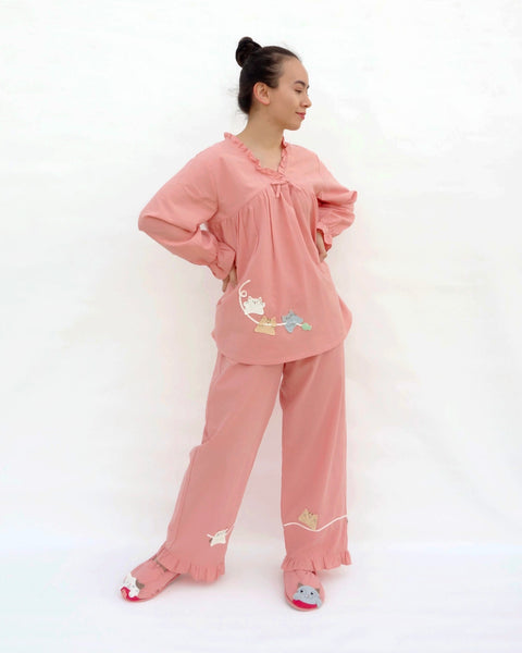 Women wearing pink pajamas with cat appliqué, embroidery details, and matching slippers in 3/4 view.