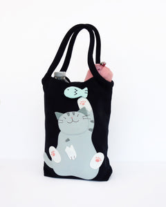 Cat Bottle-Tote in black with cotton interior, nylon lining, cat appliqué, embroidery detail, large main compartment, Velcro flap closure, sturdy double padded handles, squared off bottom for holding books, wallet, water bottle, pencil pouch, or umbrella.