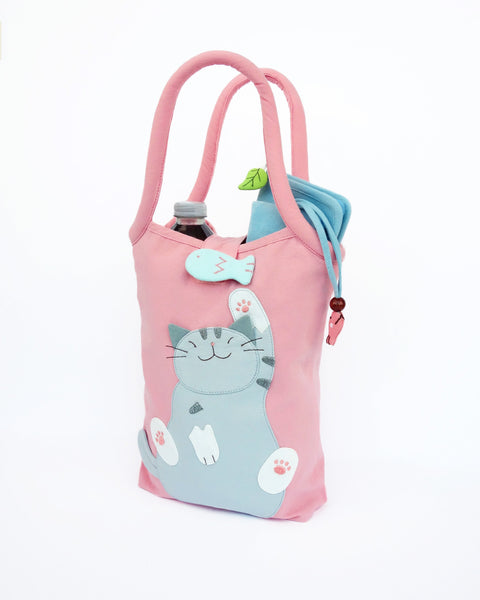 Cat Bottle-Tote in pink with cotton interior, nylon lining, cat appliqué, embroidery detail, large main compartment, Velcro flap closure, sturdy double padded handles, squared off bottom for holding books, wallet, water bottle, pencil pouch, or umbrella.