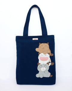 A navy blue cat-themed canvas tote bag with three appliqué cats playfully stacked on top of each other